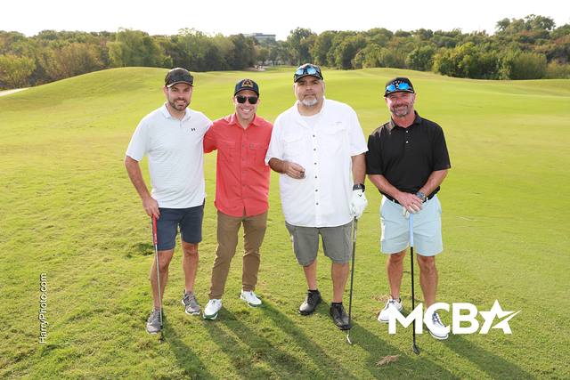 A group smiling with their clubs on the course