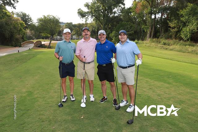 A group posing on a tee box with trees behind them
