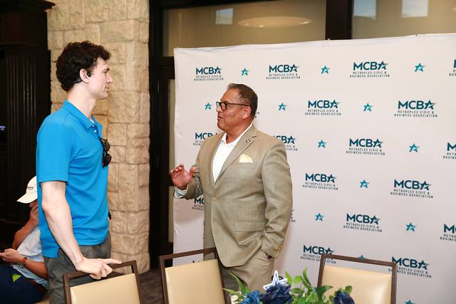 Two guests talking in front of the MCBA backdrop
