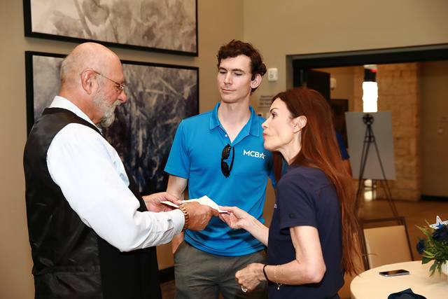 A guest talking with two MCBA team members