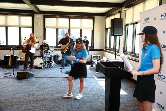 An MCBA team member at the podium with the band behind her