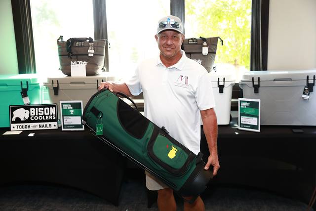 A winner holding a golf bag beside the Bison coolers
