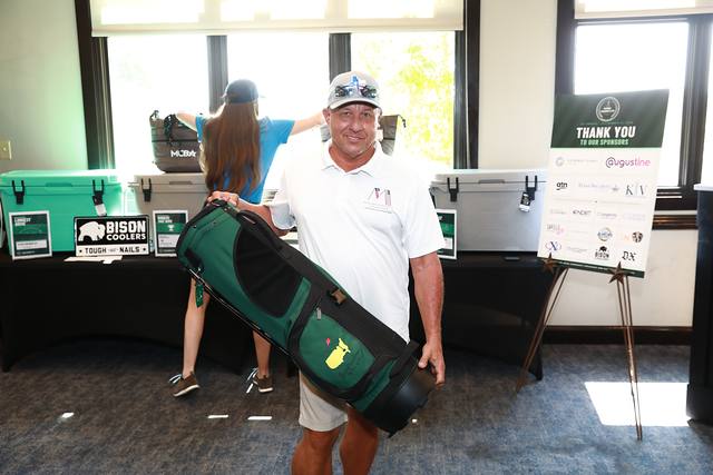 A winner with his golf bag at the prize table