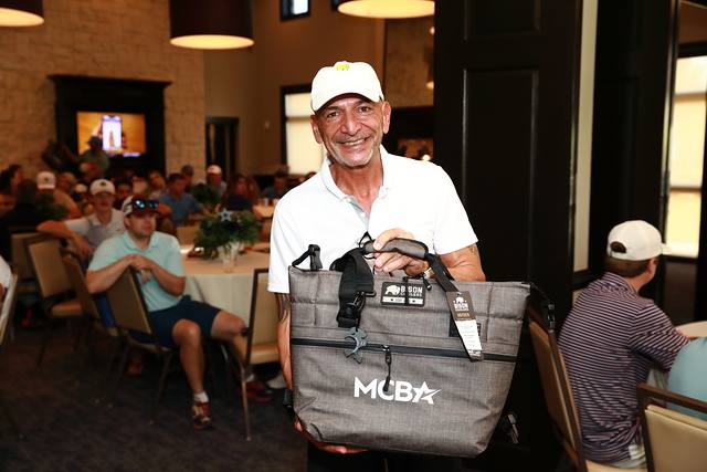 A winner holding an MCBA cooler bag at his table