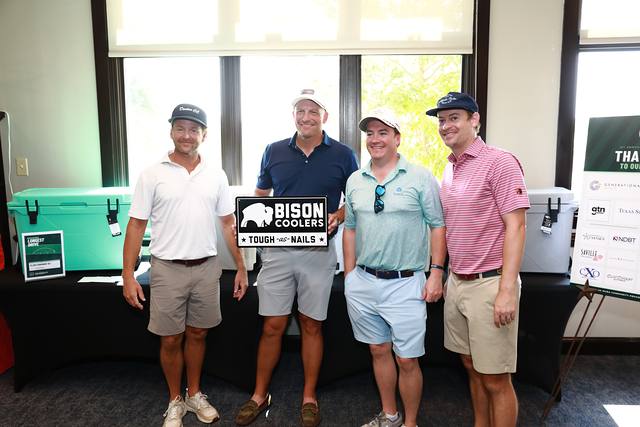 A team posing with the Bison Coolers sign at the prize table