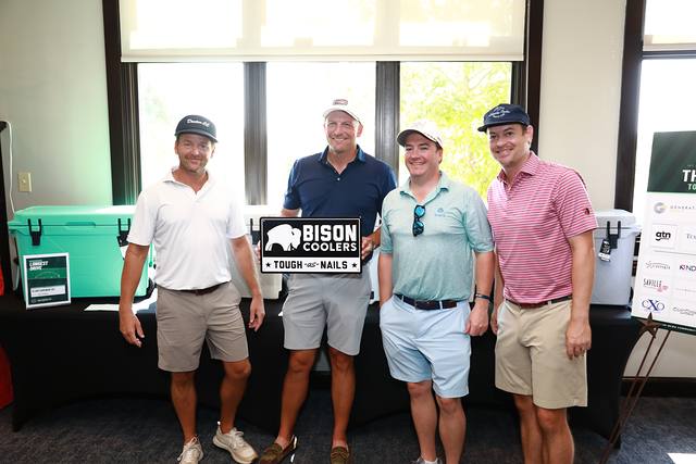 A team smiling with the Bison Coolers sign at the prize table