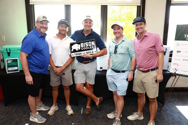 A team smiling with the Bison Coolers sign