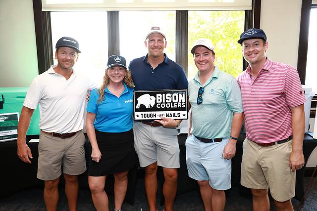A team and an MCBA team member with the Bison Coolers sign