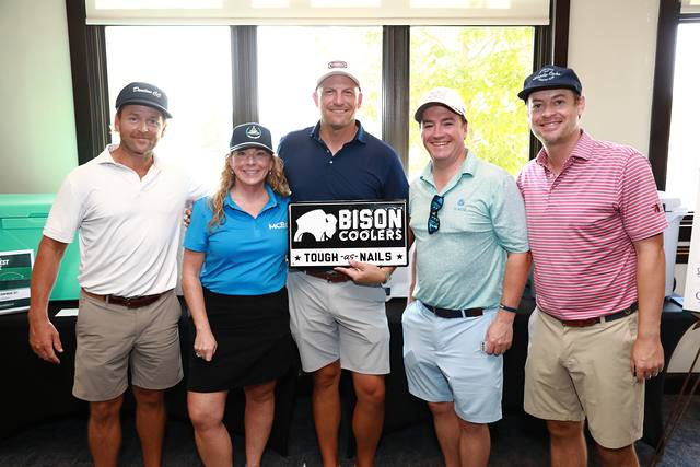 A team and an MCBA team member smiling with the Bison Coolers sign