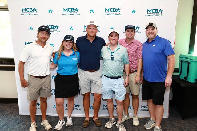 A group posing in front of the MCBA backdrop