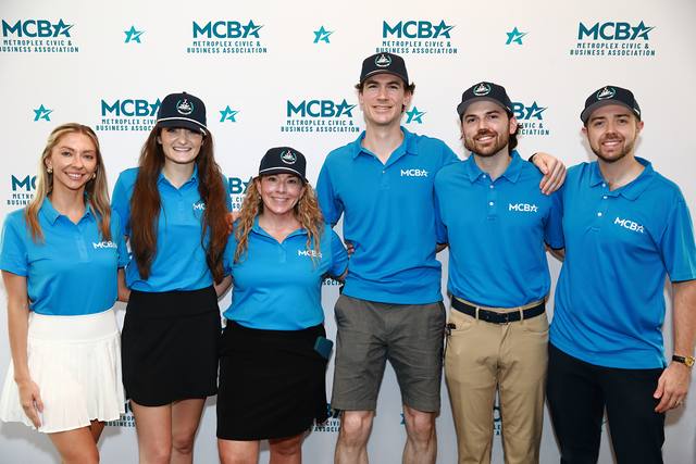 The MCBA team in front of the MCBA backdrop